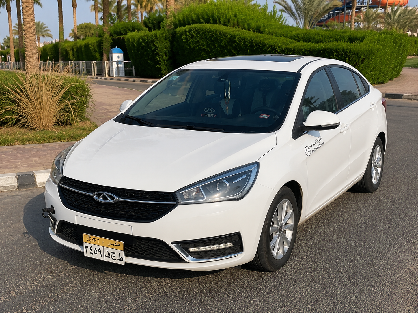 White Chery sedan parked beside a resort garden in South Sinai