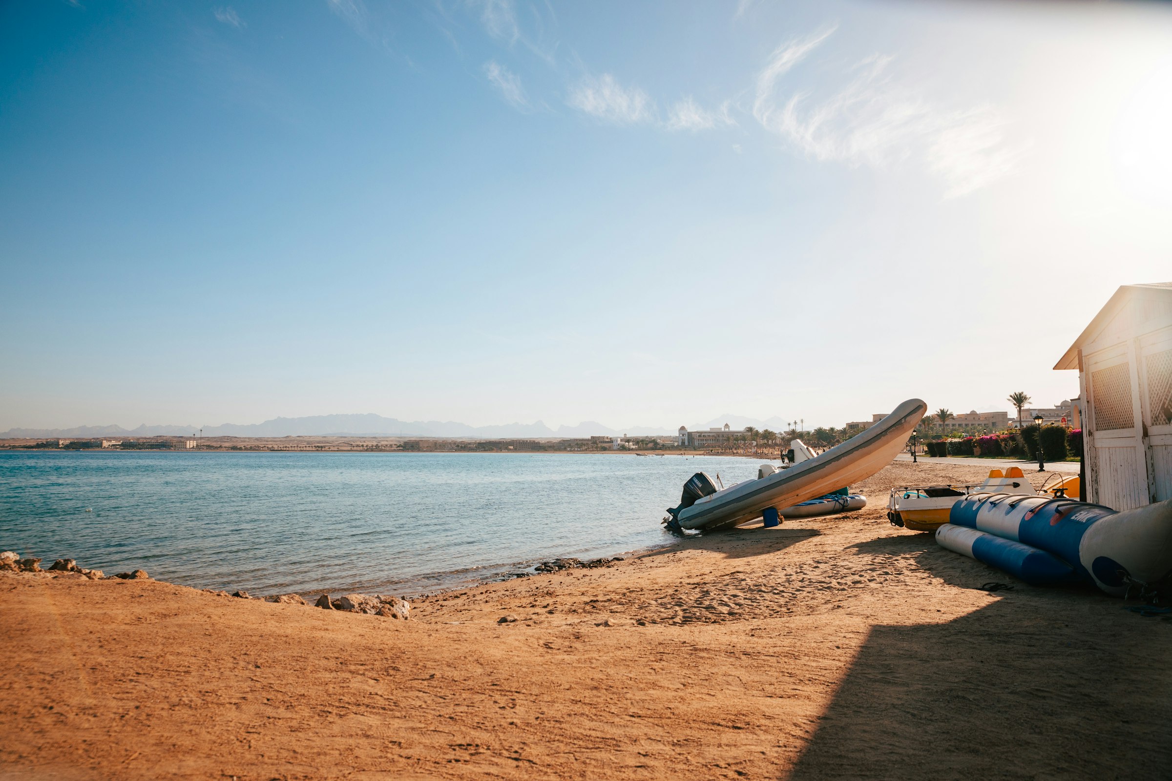 A Red Sea beach with boats and arid mountains